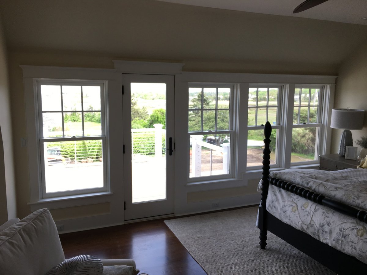 remodeled coastal bedroom with large windows and deck door by BelPort Building & Remodeling in Barnstable MA