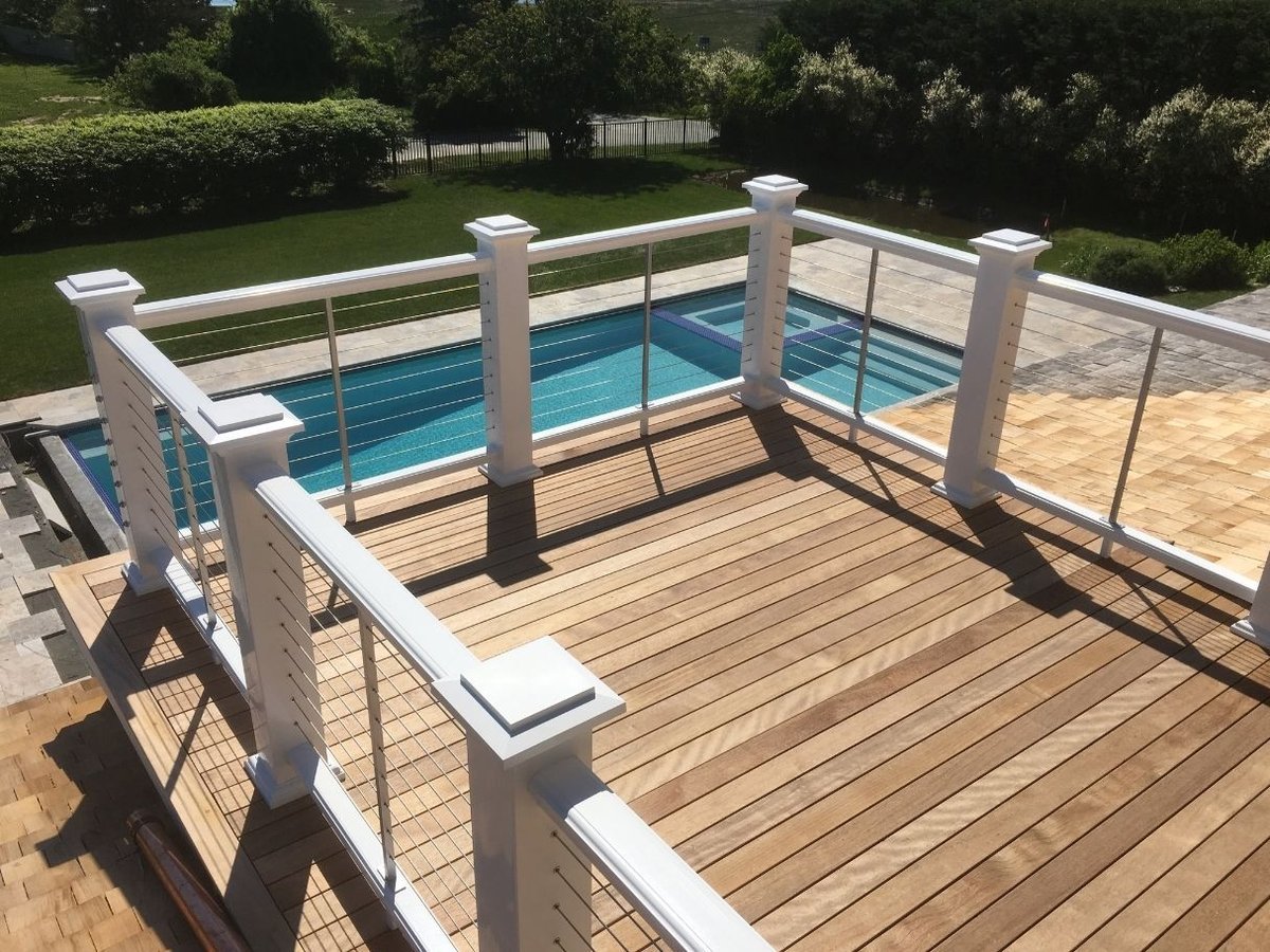 newly built deck with cable railings above pool area in Barnstable MA by BelPort Building & Remodeling